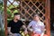 Couple of male friends look at each other on background of wooden pergola grid