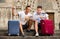 Couple of male tourists with baggage sitting with map at stairs