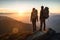 Couple of man and woman hikers on top of a mountain at sunset or sunrise