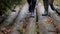 A couple, a man and a woman in rubber boots are walking through the forest.