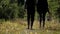 A couple, a man and a woman in rubber boots are walking through the forest.