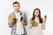 Couple man and woman standing with green detox smoothies, salad in glass bowl, burger, cola in glass bottle isolated on