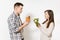 Couple man and woman standing with green detox smoothies, salad in glass bowl, burger, cola in glass bottle isolated on