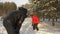 Couple man and woman throwing snowballs while winter walk in snowy forest