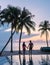 Couple of men and women relaxing by the pool in beach beds chairs, tropical pool