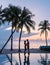 Couple of men and women relaxing by the pool in beach beds chairs, tropical pool