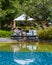 Couple of men and women relaxing by the pool in beach beds chairs, tropical pool