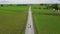 Couple men and women walking on a road between green rice field, green rice paddy field in Thailand