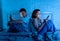 Couple on mobile phone late at night in social network addiction and relationship domestic problems