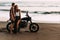 Couple on a motorcycle on the beach. A couple in love on the beach meets the sunset. A man embraces a woman on the beach.