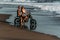 Couple on a motorcycle on the beach. A couple in love on the beach meets the sunset. A man embraces a woman on the beach.