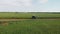 A couple of motorcyclists ride a touristic motorcycle on a dirt road. Green fields beyond the horizon. Summer day. The concept of