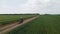 A couple of motorcyclists ride a touristic motorcycle on a dirt road. Green fields beyond the horizon. Summer day. The concept of