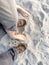 Couple with naked feet and shoes standing on the sandy beach