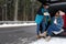 Couple near open car trunk full of luggage on road, space for text. Winter