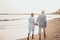 Couple of old mature people walking on the sand together and having fun on the sand of the beach enjoying and living the moment.