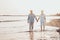 Couple of old mature people walking on the sand together and having fun on the sand of the beach enjoying and living the moment.