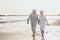 Couple of old mature people walking on the sand together and having fun on the sand of the beach enjoying and living the moment.