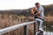 A couple on the old wooden bridge at a lake on autumn day in park. Forest on background. Happy togather, copy space for text.