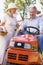 Couple outdoors with tools and lawnmower smiling