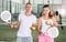 Couple with padel rackets posing on tennis court