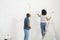 Couple paints wall in white, using rollers