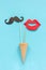 Couple paper mustache and lips props on stick in ice cream waffle cone on blue background. Concept Valentine`s Day Greeting card