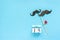 Couple paper mustache props fastened clothespin heart and calendar 15 August on blue background. Concept Homosexuality gay love.