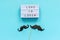 Couple paper mustache props on stick and light box with text Love is love on blue background. Concept Homosexuality gay love.