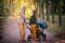 Couple of parents mom and dad walk in an autumn park with stroller for twins