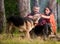 Couple pat german shepherd dog near bonfire, nature background.