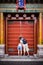A couple peeking through the small opening in a door at the Forbidden City in Beijing China