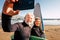 Couple of pensioners seniors taking a selfie together at the beach with their wetsuits and surfboards - mature people learning