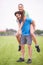 Couple, piggy back and exercise in park with portrait, smile and bonding with health in nature on grass. People, man and