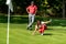 Couple playing golf, young woman reading green, getting ready to putt