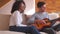 Couple playing guitar and singing on sofa at home