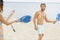 Couple playing with rackets on beach