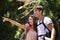 Couple, point and happy for hiking in jungle with smile for thinking, holiday and ideas on path. Man, woman and bag for