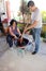 Couple of poor adult man and woman cook Mexican mole in clay pot on a stove mixing with wooden spoon in the patio of the house in