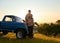 Couple, portrait and sunset by pickup truck in nature for road trip with love, romance and date on adventure. Man, woman