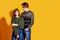 Couple posing in jeans type commercial fashion style on yellow wall