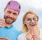 Couple posing with party props sky background. Humor and laugh concept. Photo booth props. Man with beard and woman