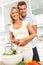 Couple Preparing Salad In Modern Kitchen