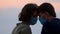 Couple in protective masks. Side view close up faces of man and woman in medical mask touches foreheads moment of