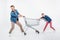 Couple pulling empty shopping cart and looking away on white