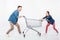 Couple pulling empty shopping cart and looking on each other on white