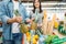 Couple puts pineapple into the cart in supermarket