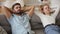 Couple putting hands behind head resting on couch feels good