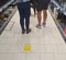 A couple queuing in a supermarket not standing on the marker that shows them how to be two meters apart, ignoring the social dista