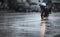 A couple with raincoat on a motorbike during hard rainfall.